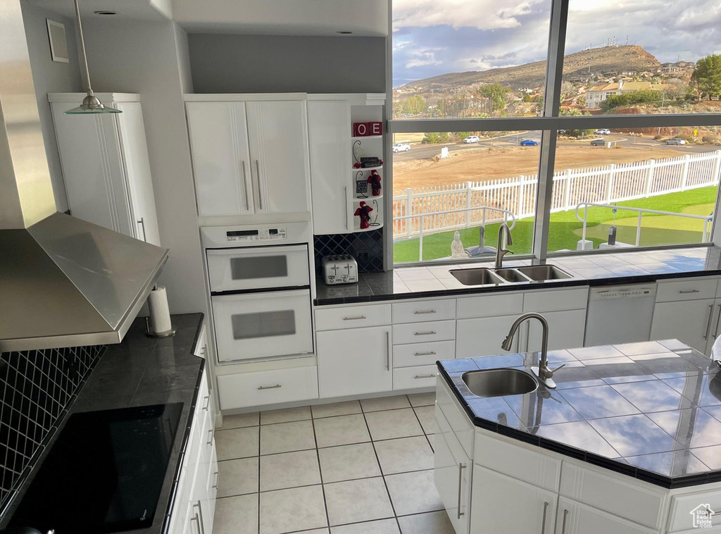 Kitchen with white cabinets, white appliances, sink, and backsplash