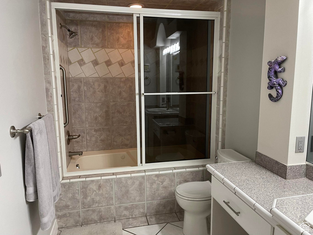 Full bathroom featuring tile flooring, enclosed tub / shower combo, toilet, and vanity