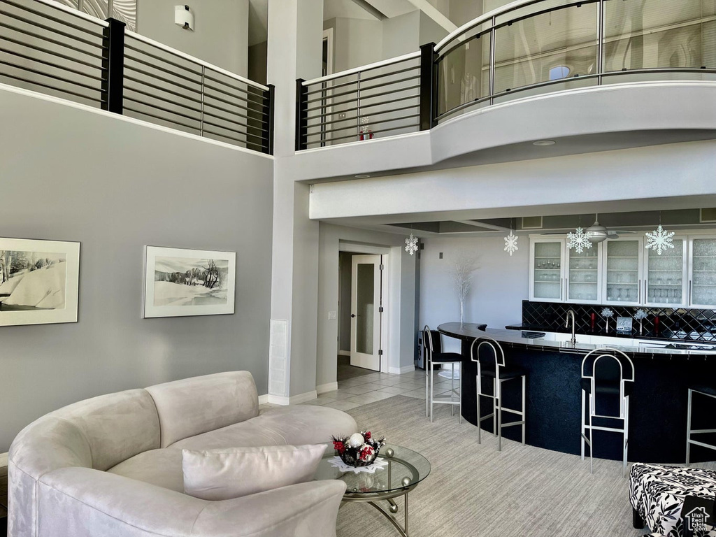 Living room with light tile flooring, a towering ceiling, sink, and ceiling fan