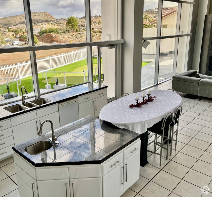 Kitchen with white cabinets, a kitchen island with sink, dishwasher, and sink