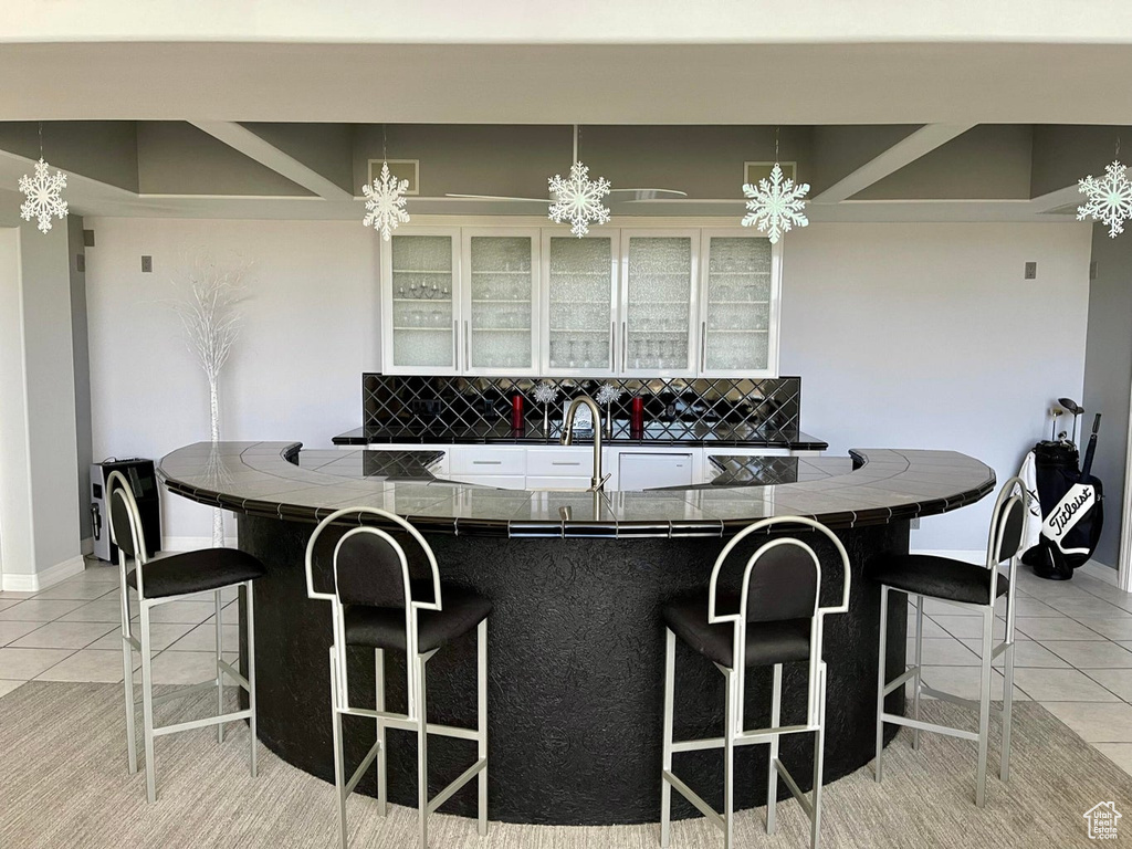 Kitchen with light tile flooring, a breakfast bar, tasteful backsplash, kitchen peninsula, and an inviting chandelier