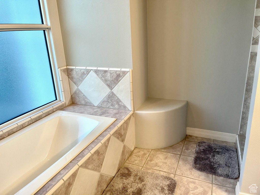 Bathroom with plenty of natural light, a relaxing tiled bath, and tile floors