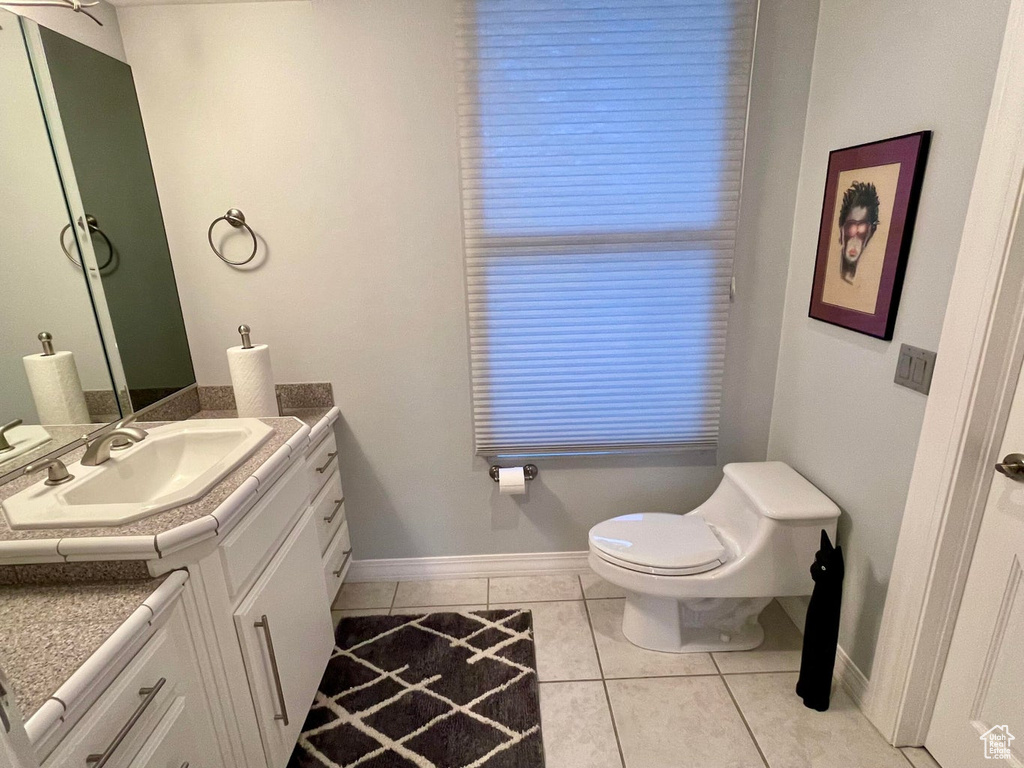 Bathroom with toilet, vanity with extensive cabinet space, and tile floors