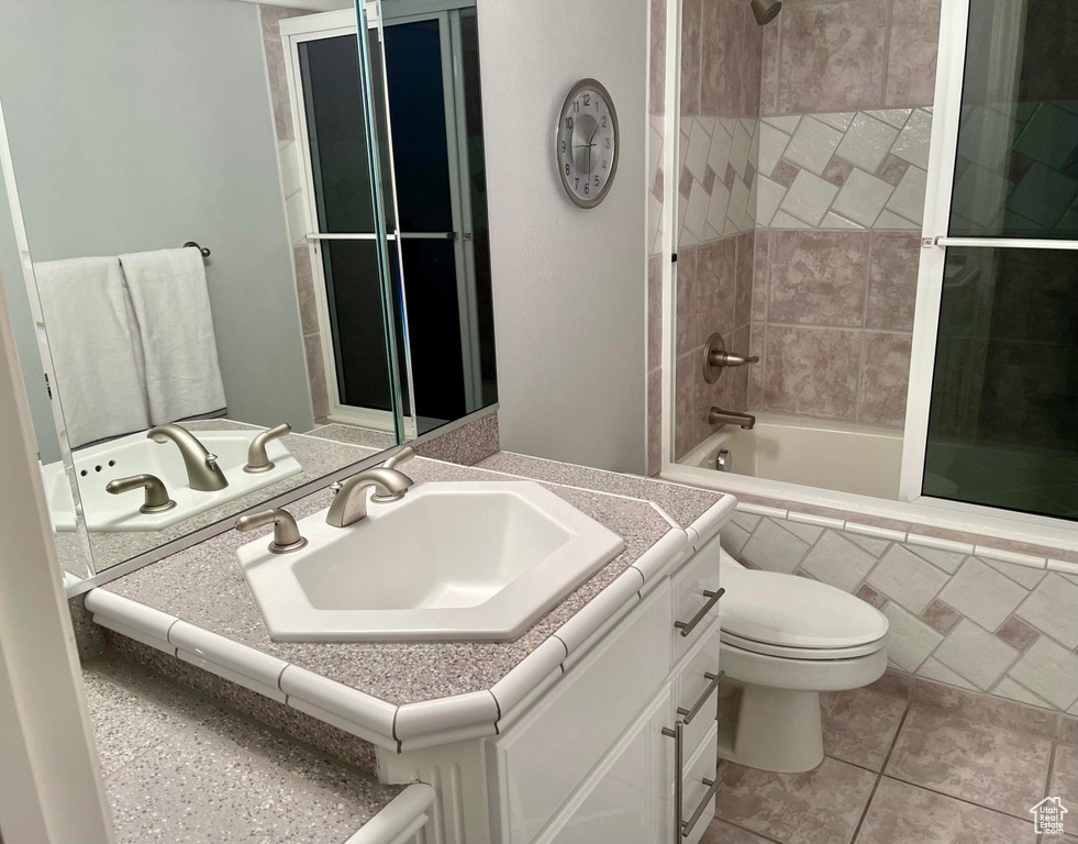 Full bathroom featuring tiled shower / bath, tile floors, toilet, and vanity