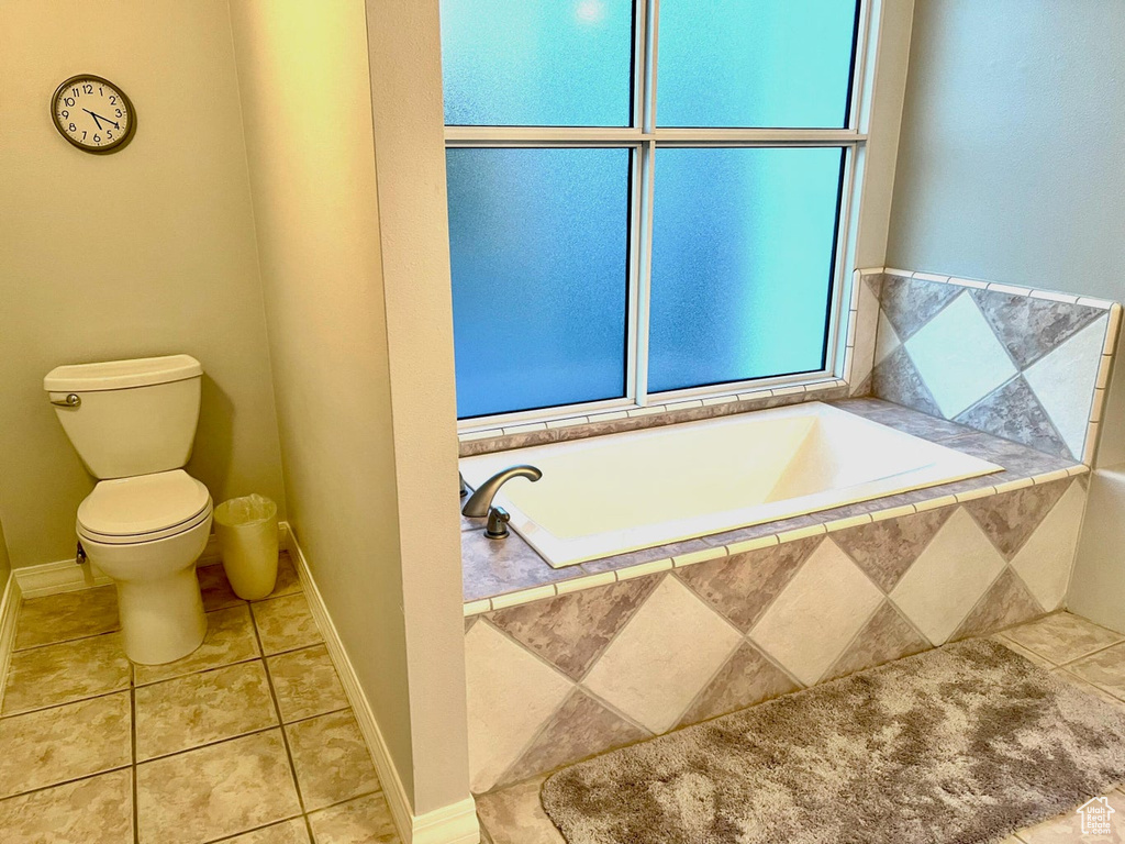 Bathroom featuring tile flooring, tiled tub, and toilet