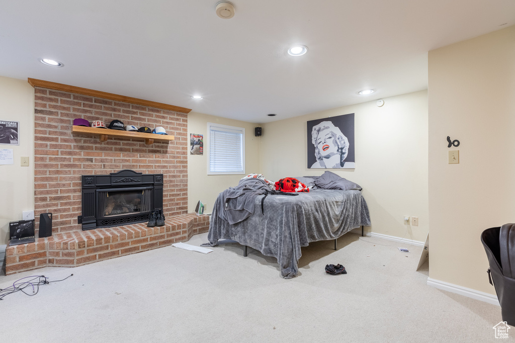 Bedroom with a brick fireplace, light colored carpet, and brick wall