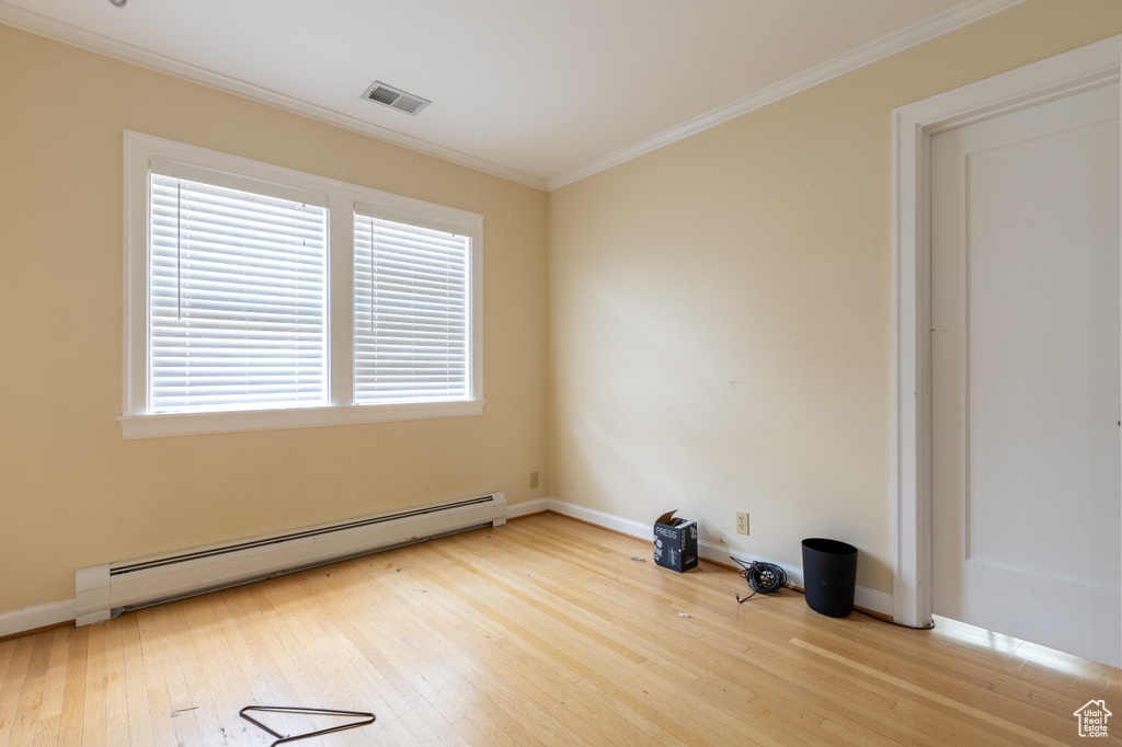 Unfurnished room with a baseboard radiator, ornamental molding, and light wood-type flooring
