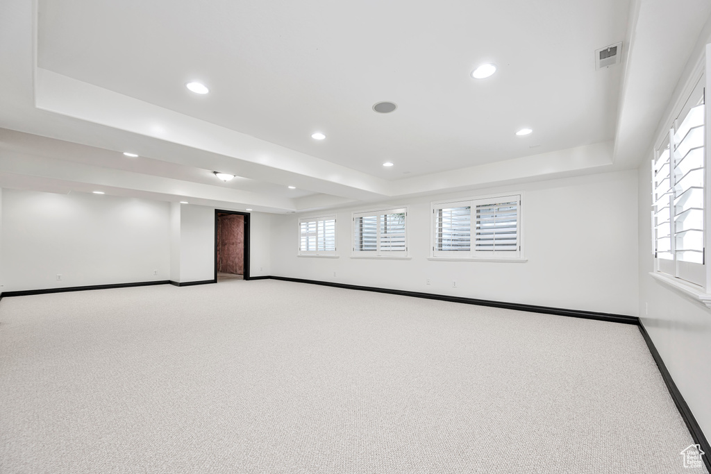 Empty room featuring light colored carpet, plenty of natural light, and a raised ceiling