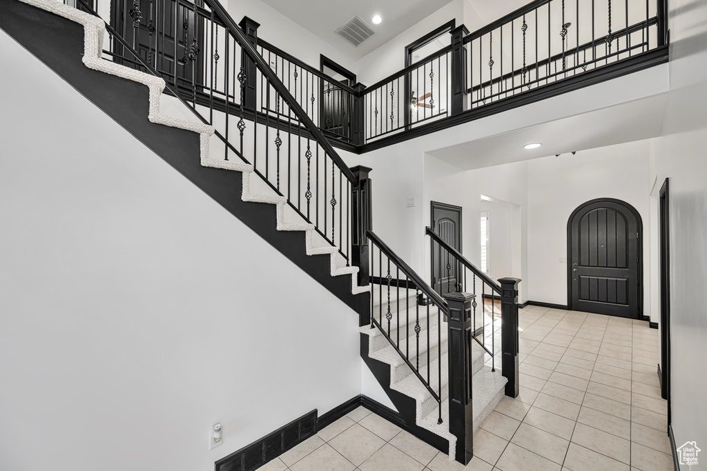 Stairs featuring light tile floors and a high ceiling