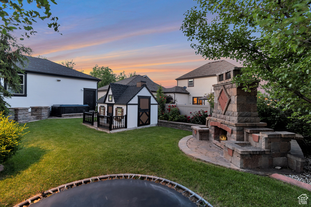 Yard at dusk with an outdoor stone fireplace and a storage shed