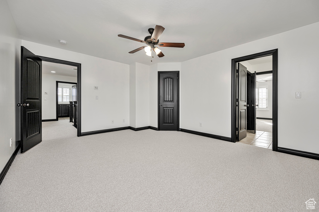 Carpeted spare room with a wealth of natural light and ceiling fan