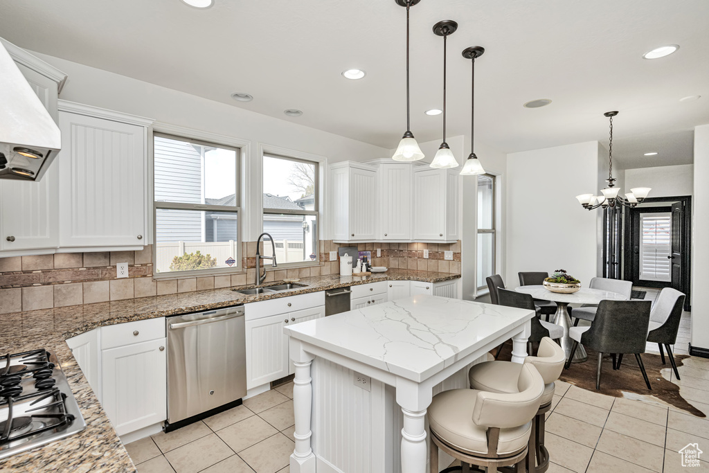 Kitchen featuring tasteful backsplash, sink, appliances with stainless steel finishes, decorative light fixtures, and an inviting chandelier