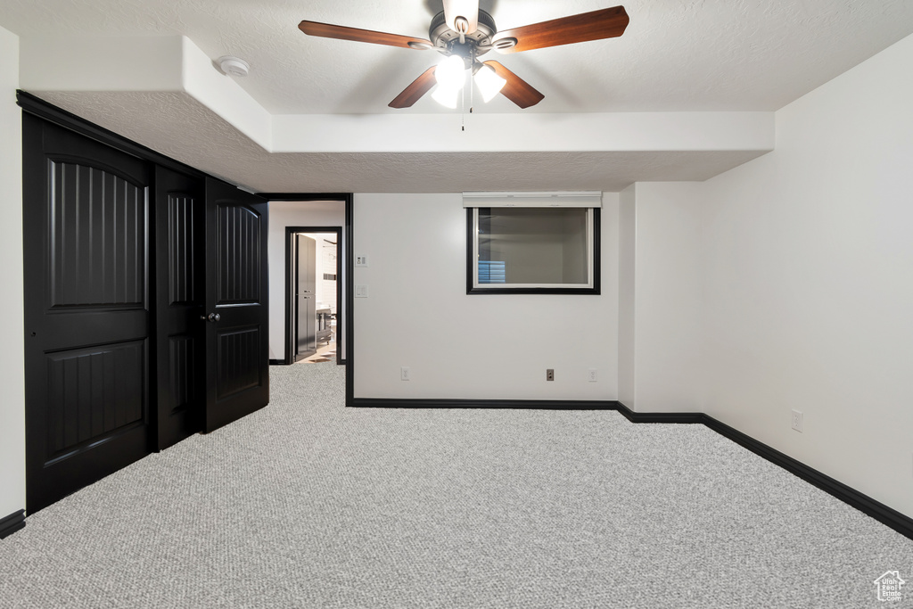 Unfurnished bedroom featuring light colored carpet, a closet, a textured ceiling, and ceiling fan