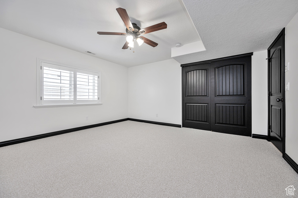 Unfurnished bedroom with carpet floors, a textured ceiling, ceiling fan, and a closet