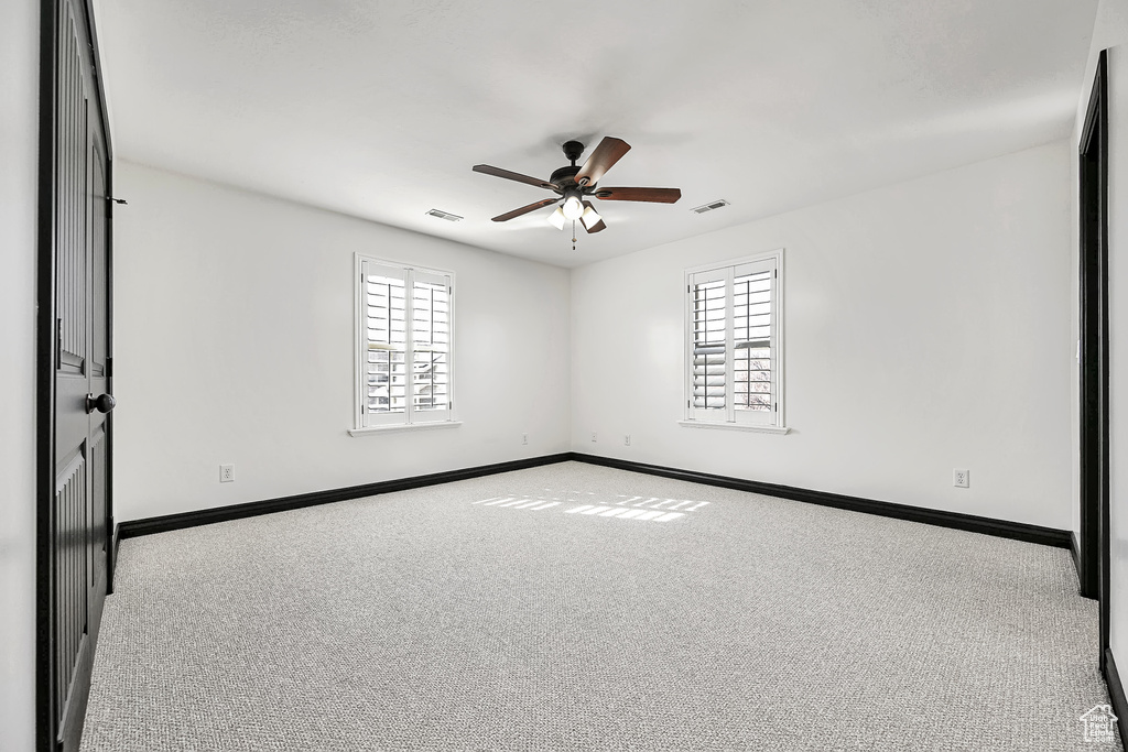 Carpeted spare room with ceiling fan and a healthy amount of sunlight