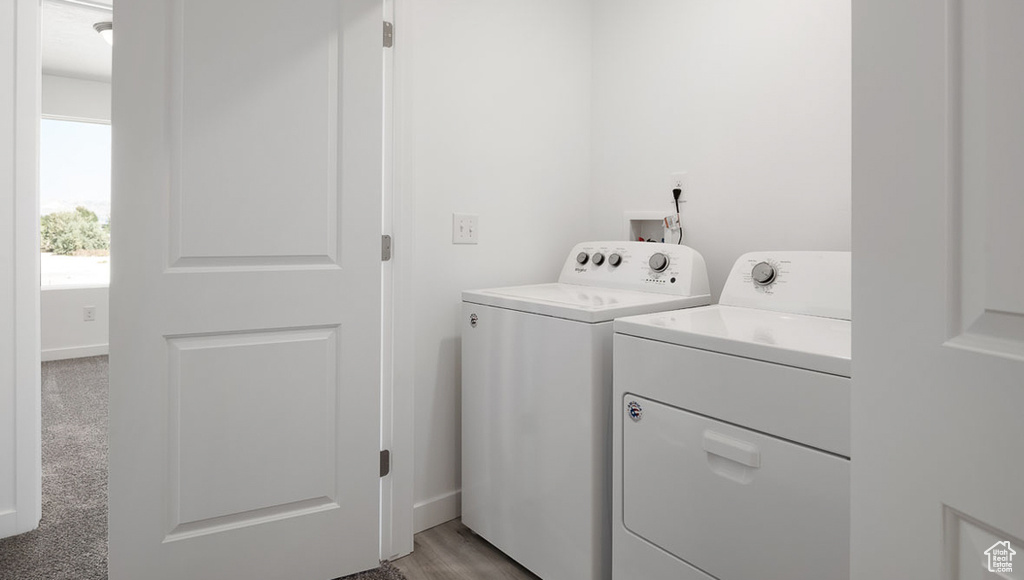 Washroom with hookup for a washing machine, light carpet, and washer and dryer