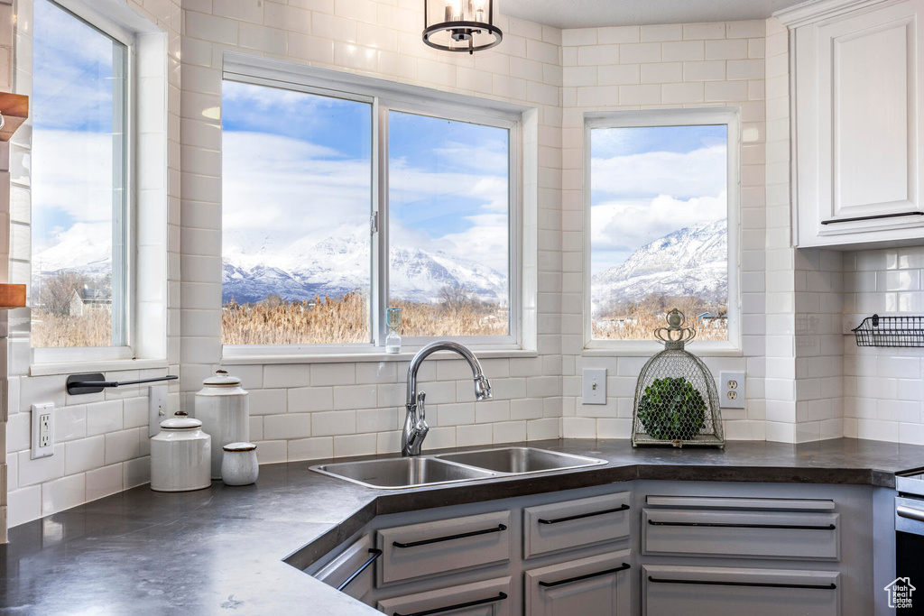 Kitchen with white cabinetry, sink, a mountain view, backsplash, and an inviting chandelier