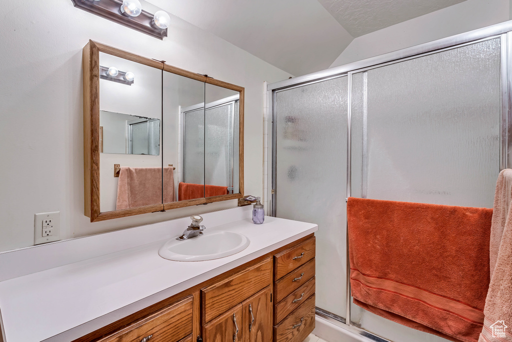 Bathroom with an enclosed shower, vanity, and lofted ceiling