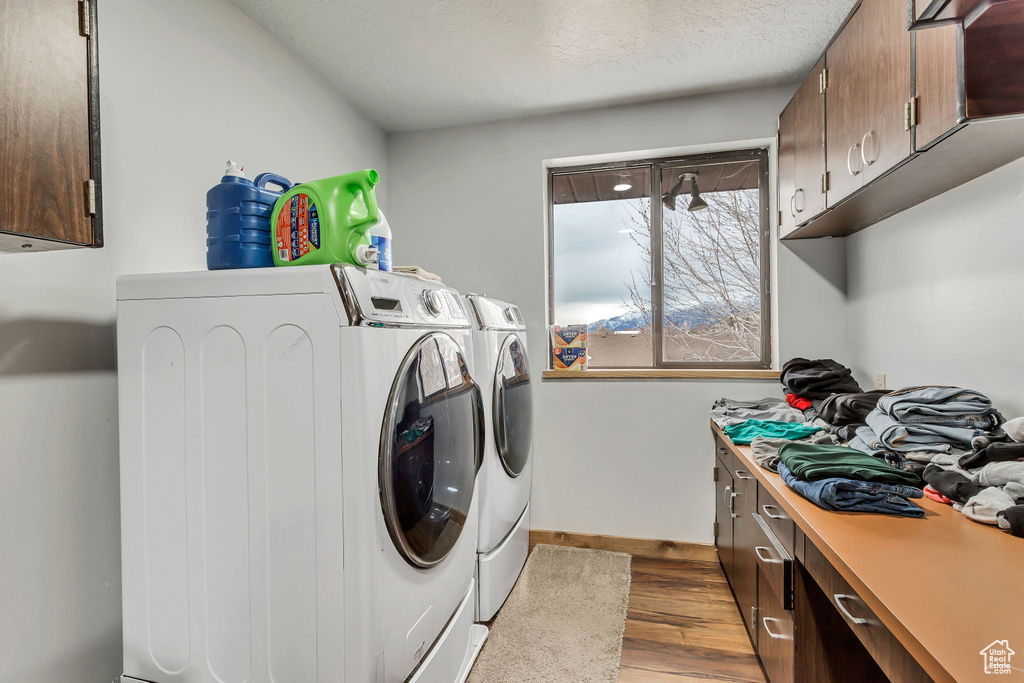Washroom with cabinets, washer and clothes dryer, and light hardwood / wood-style floors