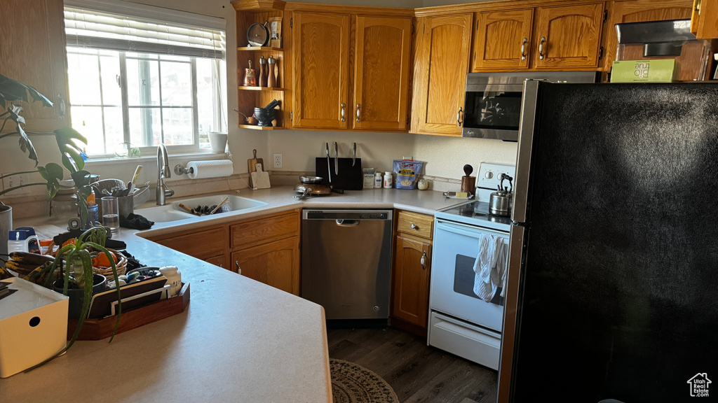Kitchen featuring sink, refrigerator, dishwasher, dark wood-type flooring, and white range with electric cooktop