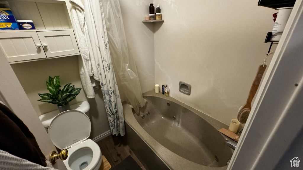 Bathroom with toilet, shower / bath combo with shower curtain, and hardwood / wood-style floors