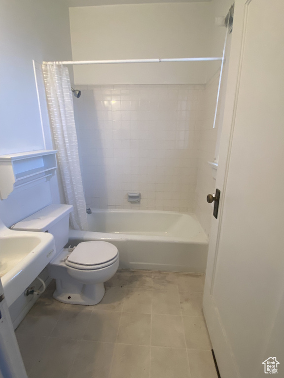 Bathroom featuring toilet, shower / tub combo, and tile floors