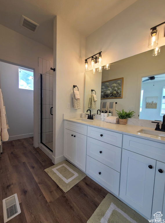 Bathroom with dual bowl vanity, an enclosed shower, and hardwood / wood-style floors