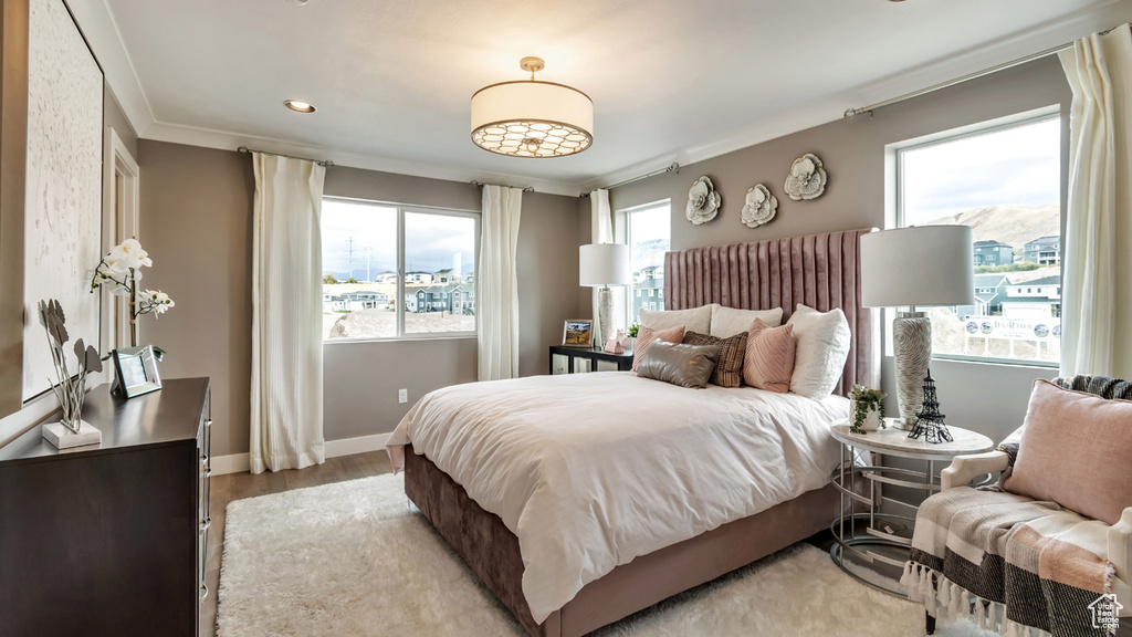 Bedroom with ornamental molding and light hardwood / wood-style floors