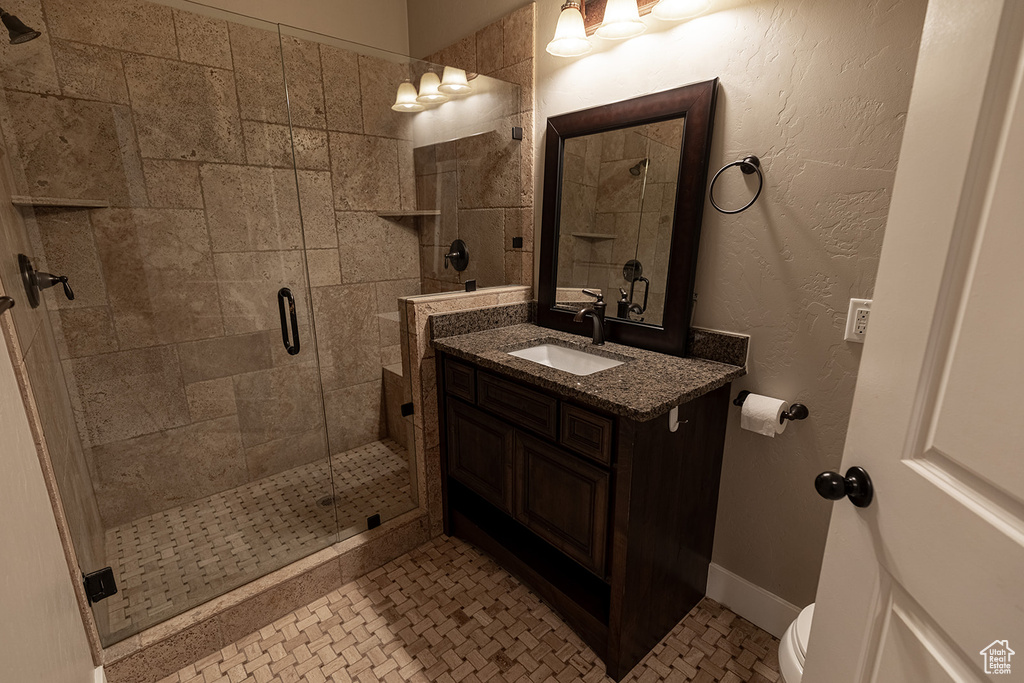 Bathroom featuring a shower with door, tile floors, oversized vanity, and toilet