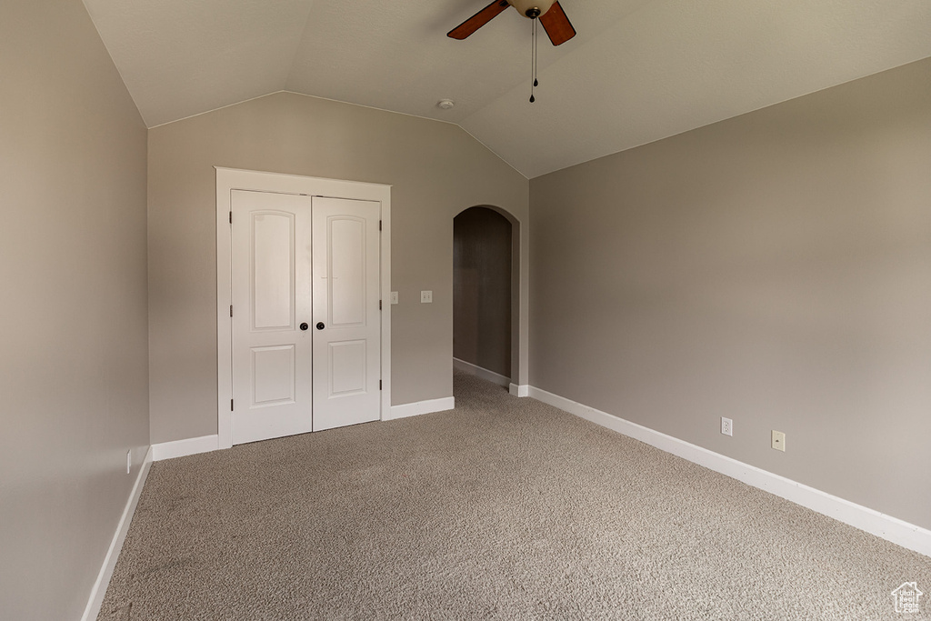 Unfurnished bedroom featuring light carpet, ceiling fan, vaulted ceiling, and a closet