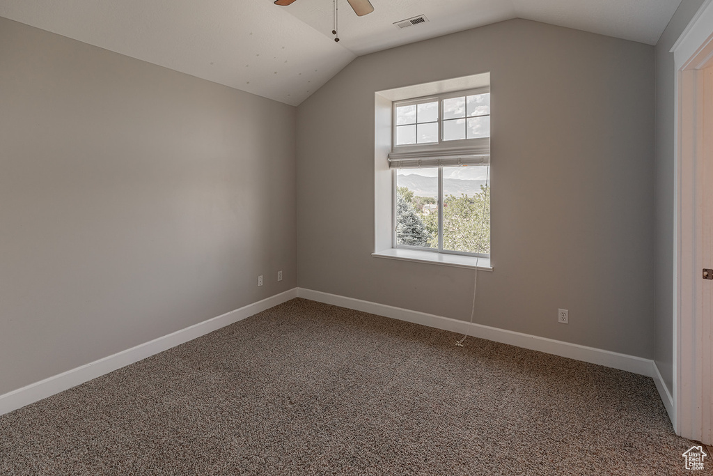 Additional living space with dark carpet, ceiling fan, and lofted ceiling