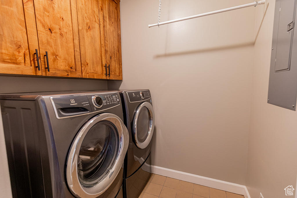 Laundry area featuring light tile flooring, washing machine and dryer, and cabinets
