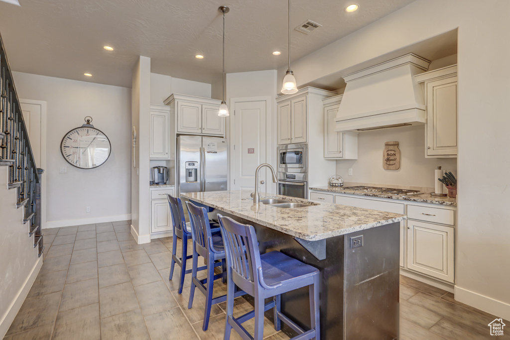 Kitchen with premium range hood, a kitchen island with sink, stainless steel appliances, and sink