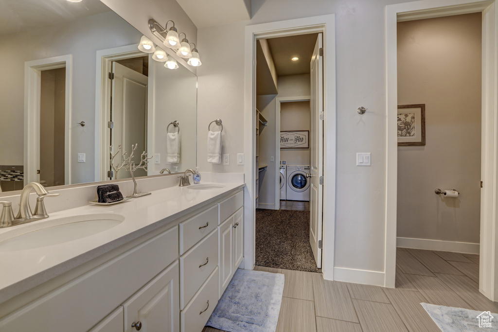 Bathroom with tile flooring, washer and clothes dryer, and dual bowl vanity