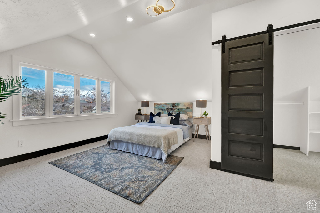 Bedroom featuring vaulted ceiling, light colored carpet, and a barn door