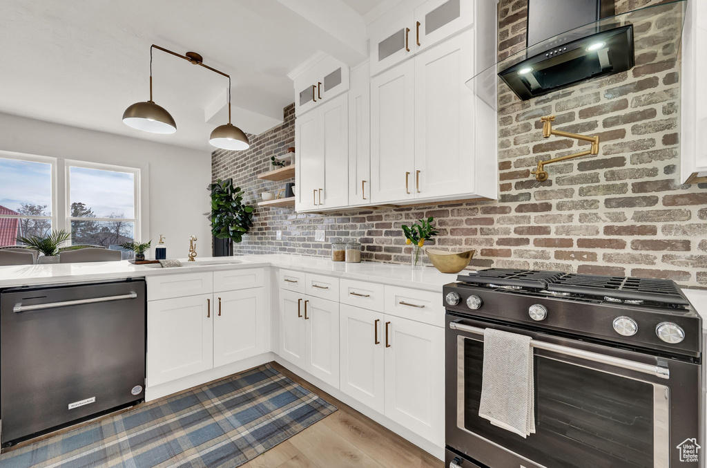 Kitchen featuring white cabinets, stainless steel appliances, light hardwood / wood-style floors, sink, and pendant lighting
