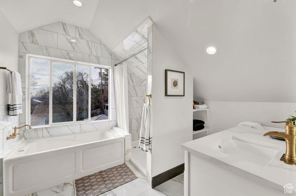 Bathroom with vaulted ceiling, shower with separate bathtub, tile flooring, and sink