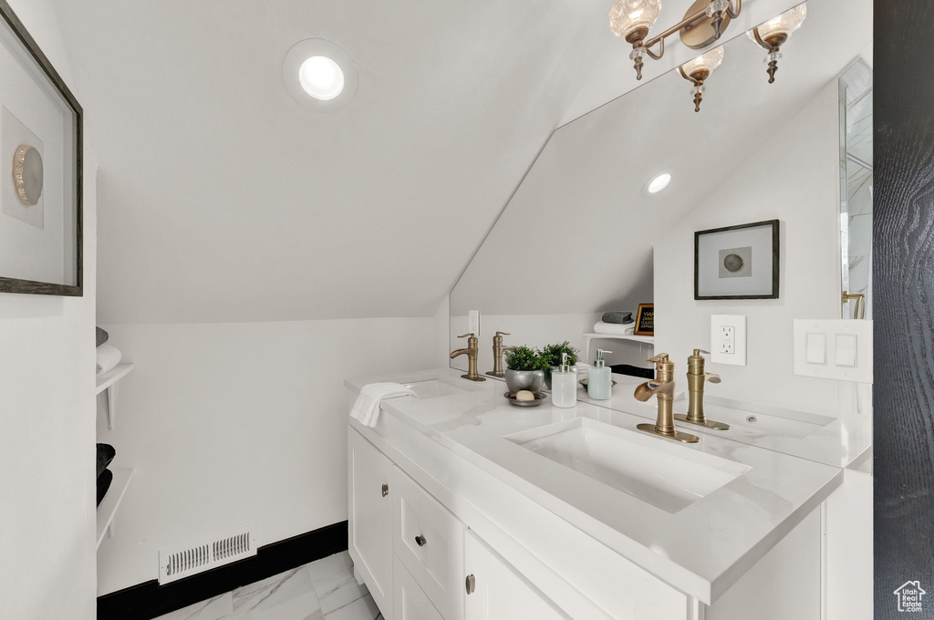 Bathroom featuring vanity, vaulted ceiling, a chandelier, and tile floors