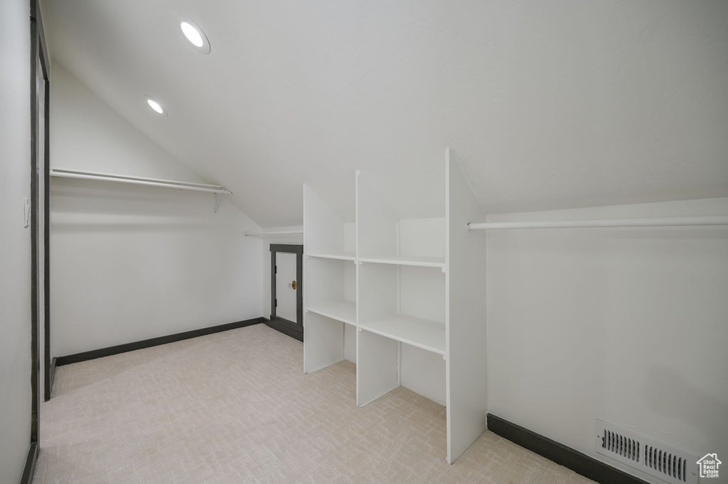 Spacious closet with vaulted ceiling and light carpet