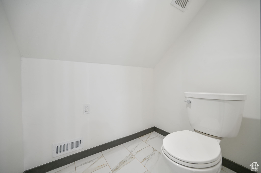 Bathroom with vaulted ceiling, toilet, and tile floors