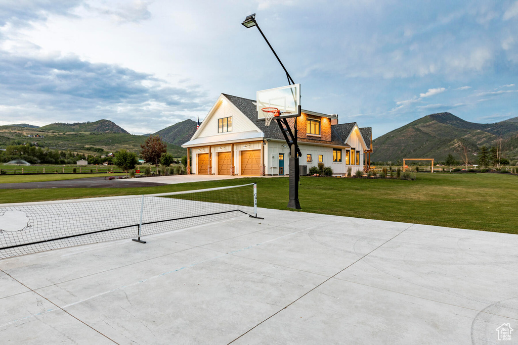 Exterior space with basketball hoop, a yard, a mountain view, and a garage