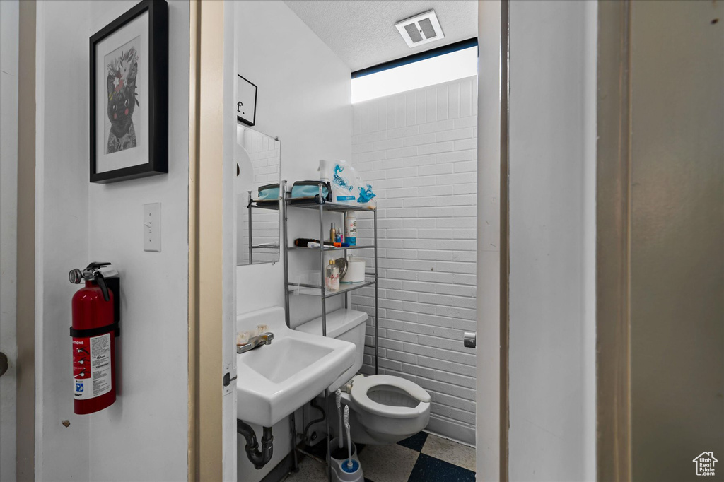 Bathroom featuring a textured ceiling, toilet, tile floors, and sink