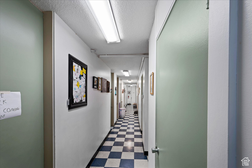 Hallway with a textured ceiling and dark tile flooring