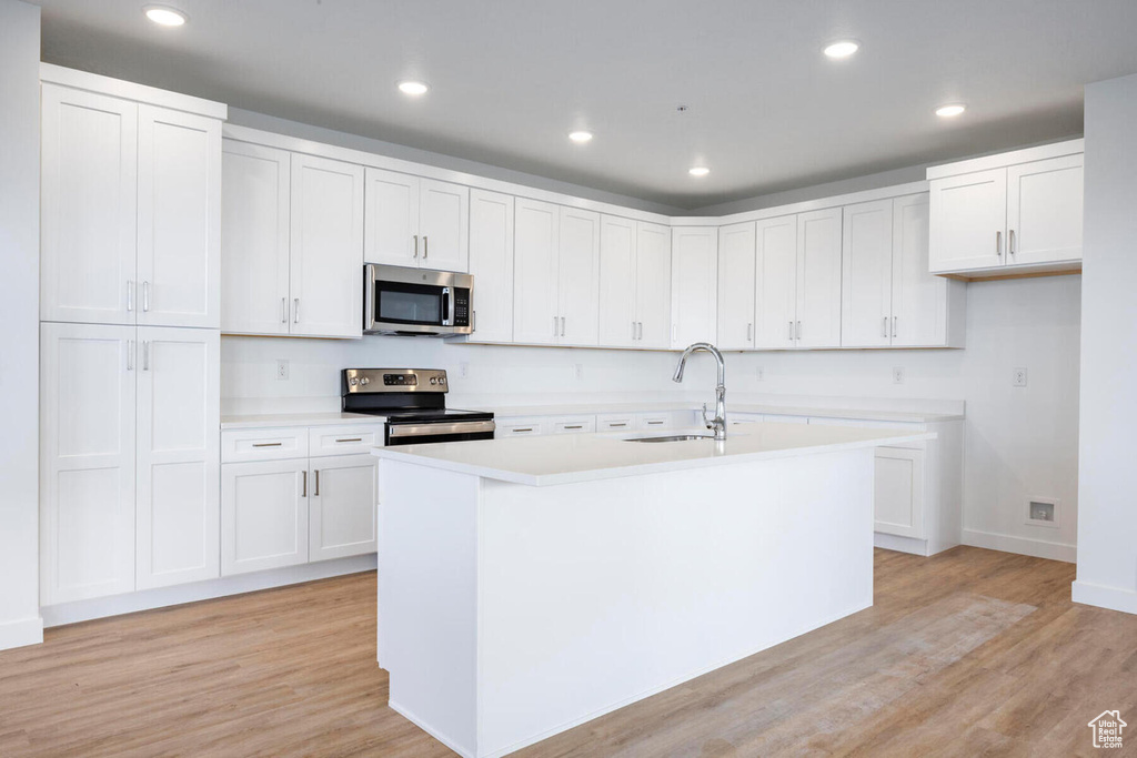 Kitchen featuring white cabinets, stainless steel appliances, and light hardwood / wood-style floors