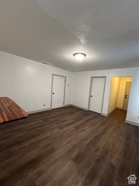 Unfurnished bedroom with dark hardwood / wood-style flooring and a textured ceiling
