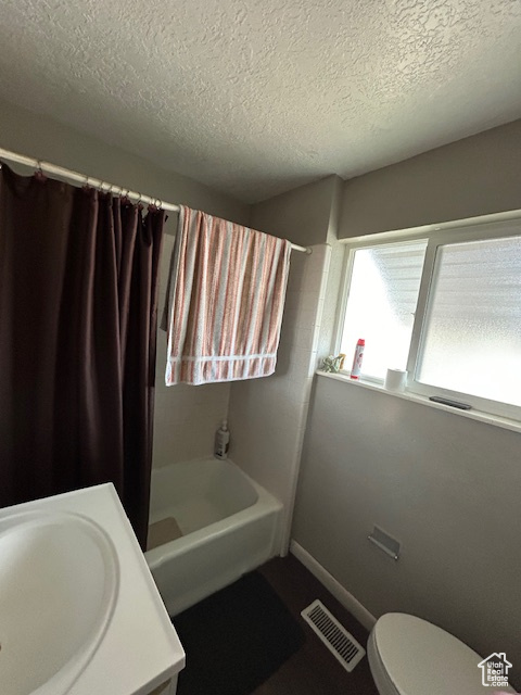 Full bathroom with shower / tub combo with curtain, toilet, a textured ceiling, and vanity