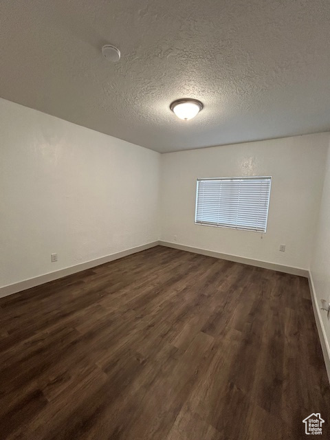 Spare room featuring dark hardwood / wood-style flooring and a textured ceiling