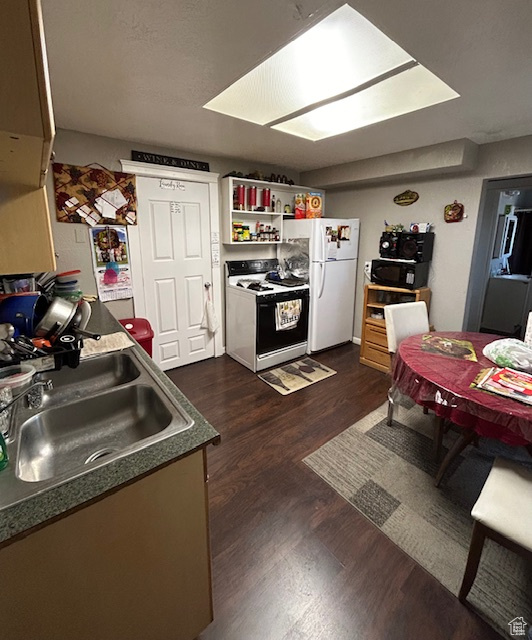 Kitchen featuring white fridge, stove, sink, and dark wood-type flooring