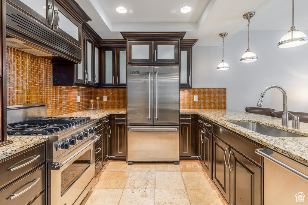 Kitchen featuring backsplash, sink, hanging light fixtures, and premium appliances