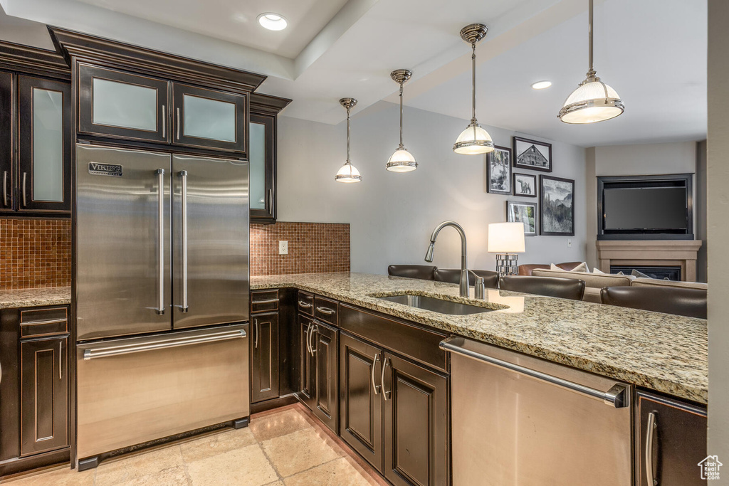 Kitchen featuring sink, pendant lighting, tasteful backsplash, appliances with stainless steel finishes, and light stone counters